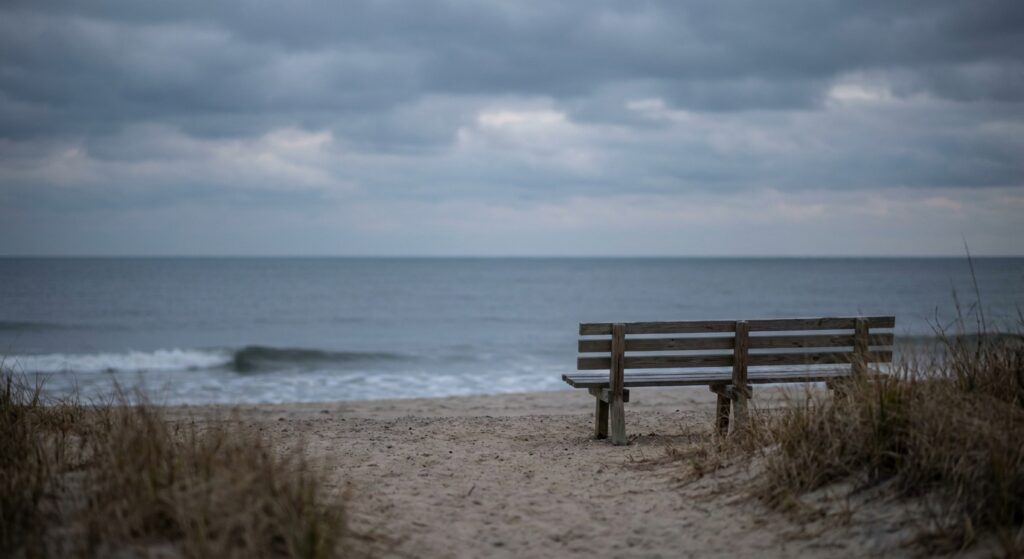 Empty bench facing the ocean at dusk on a New Jersey beach, symbolizing the solitude and reflection that often accompany living with serious mental illness