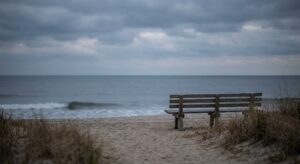 Empty bench facing the ocean at dusk on a New Jersey beach, symbolizing the solitude and reflection that often accompany living with serious mental illness